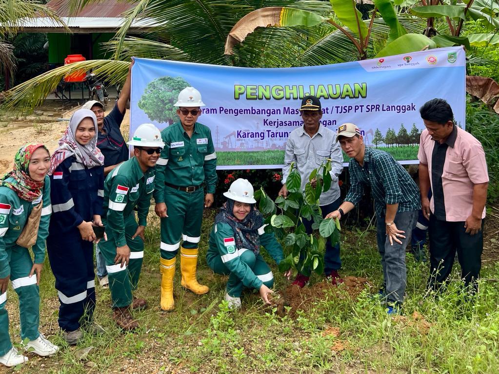 Yunida Mahpuzoh, Business Support Manager PT SPR Langgak sedang menanam pohon di pinggir jalan Desa Koto Tandun didampingi Muhammad Tohsin, Kepala Desa Koto Tandun (bertopi, dua dari kanan) dan staff PT SPR Langgak serta apartur desa.